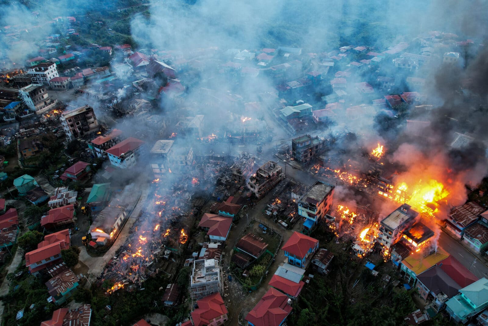 Luftaufnahme eines Dorfes in Myanmar nach einem Luftangriff mit brennenden Häusern